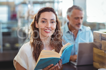 Pretty brunette looking at camera and holding book