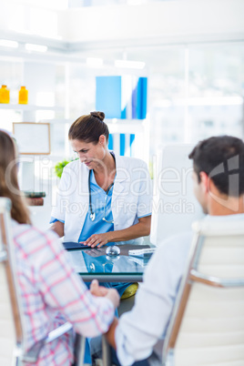 Rear view of pregnant woman and her husband discussing with doct