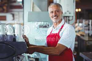 Happy barista smiling at camera and using the coffee machine