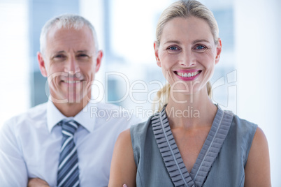 Two business people smiling at the camera in the office