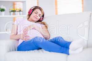 Pregnant woman listening music and touching her belly