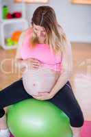 Pregnant woman touching her belly on exercise ball