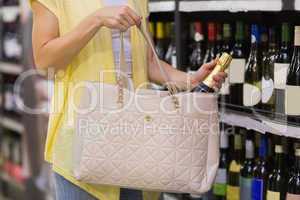 Pretty woman putting a champagne bottle in her bag