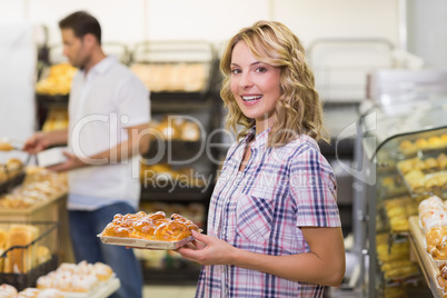 Portrait of a smiling blonde woman taking a pastry
