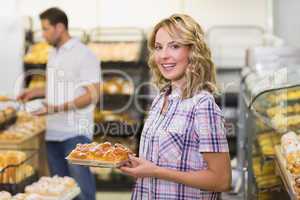 Portrait of a smiling blonde woman taking a pastry