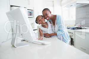 Happy smiling mother with her daughter using computer