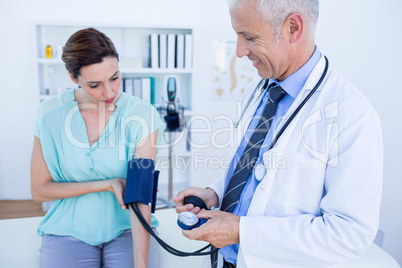 Doctor checking blood pressure of a young woman