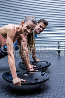 Muscular couple doing bosu ball exercises