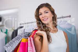 Portrait of smiling woman holding shopping bag and looking at ca