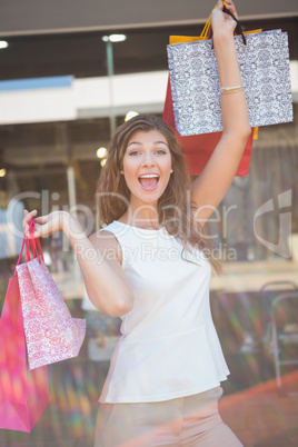 Portrait of euphoric woman raising shopping bags