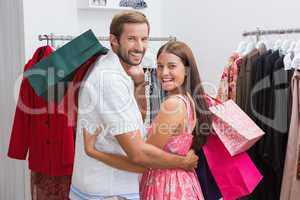 Portrait of smiling couple with shopping bags embracing