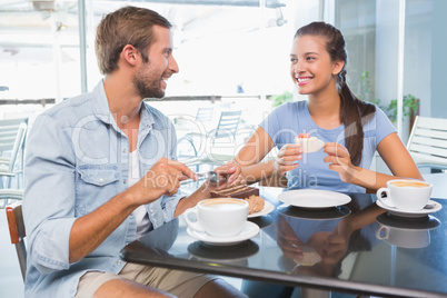 Young happy couple eating cake together