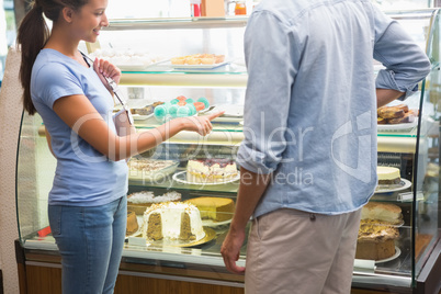 Young happy couple choosing cake