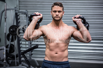 Portrait of muscular man lifting two kettlebells