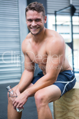 Portrait of smiling muscular man sitting and looking at camera