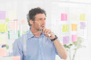 Puzzled businessman looking post its on the wall