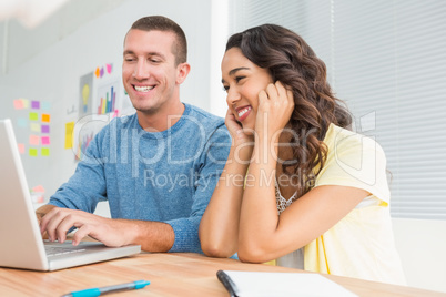 Smiling colleagues working together with laptop