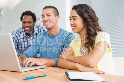 Smiling colleagues working together with laptop