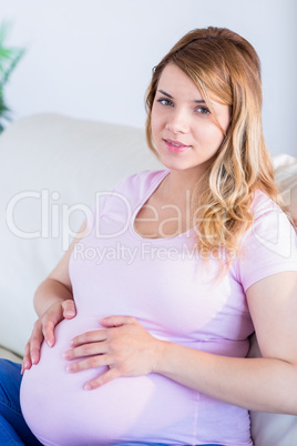 Pregnant woman looking at camera with hands on belly