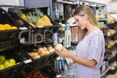 Smiling pretty blonde woman buying onions