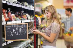 Smiling pretty blonde woman buying a vegetables