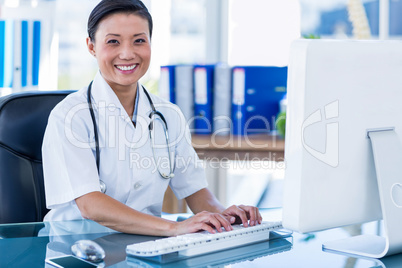 Happy doctor using her computer and looking at camera