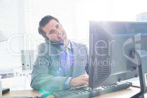 Businessman having phone call while using his computer