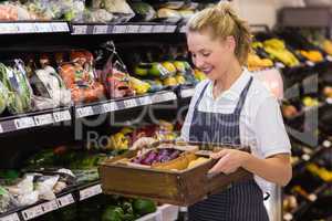 Smiling blonde worker holding a box with vegetables