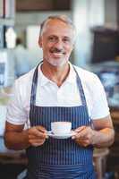 Waiter smiling and holding cup of coffee