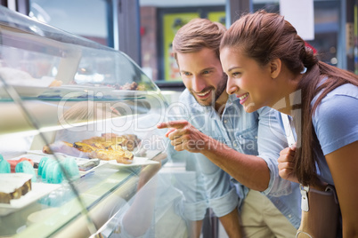 Young happy couple choosing cake