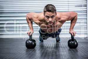 Portrait of muscular man doing push-ups with kettlebells