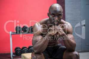 Young Bodybuilder sitting on a wooden Block