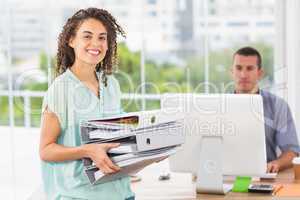 Smiling businesswoman carrying a stack of folders