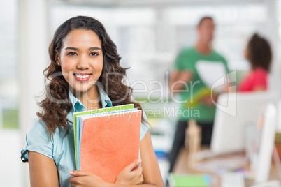 businesswoman holding files with her colleagues behind her