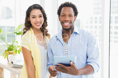 Young smiling business people holding and using a digital tablet