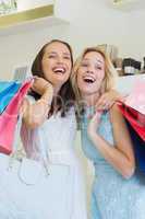 Happy women laughing together and holding shopping bags