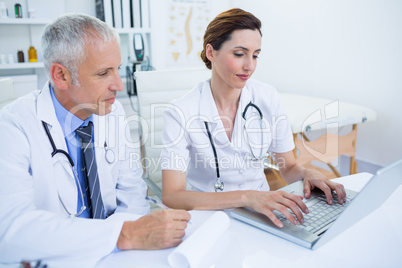 Smiling medical colleagues working with laptop