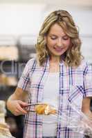 Smiling pretty blonde taking a bread with tongs