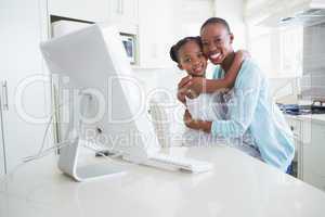 Happy smiling mother with her daughter using computer