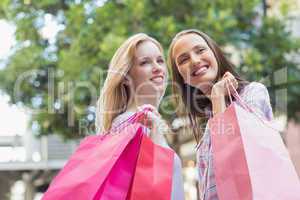 Happy women with shopping bags looking away
