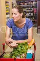 Thoughtful pretty woman pushing trolley