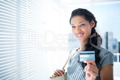 Smiling businesswoman looking at camera with credit card