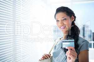 Smiling businesswoman looking at camera with credit card
