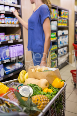 Casual woman taking product on shelf