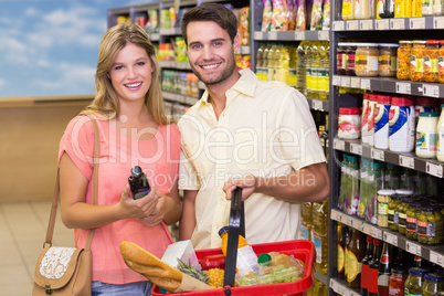 Portrait of smiling bright couple buying food products using sho