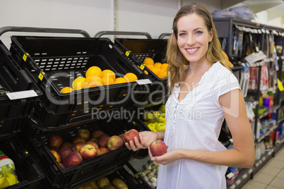 Smiling pretty blonde woman buying an apple