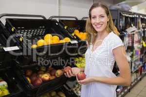 Smiling pretty blonde woman buying an apple