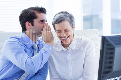 Two business people looking at a paper while working on computer