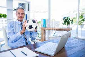 Happy businessman looking at camera and holding foot ball