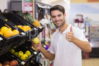 Portrait of a smiling handsome man buying a fruit with thumb up